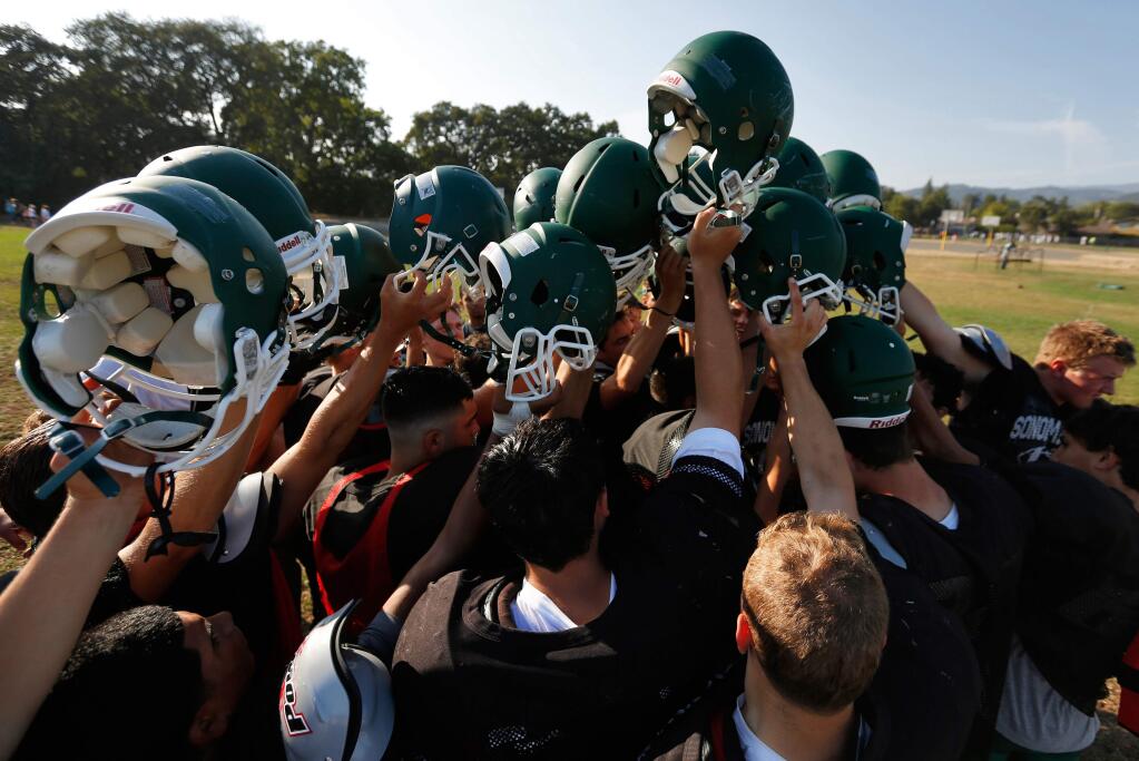 The Sonoma Valley Dragons raise their helmets in a cheer after varsity football practice in Sonoma on August 18, 2015. (Alvin Jornada / The Press Democrat)