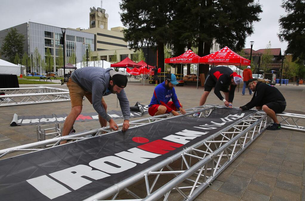 Andrew McQuillan, left, Sam Jones, Shane Smith, and Juan Gutierrez attach an Ironman Village sign to a truss, for the upcoming Ironman 70.3 Santa Rosa, at Old Courthouse Square in Santa Rosa on Wednesday, May 10, 2017. (Christopher Chung/ The Press Democrat)