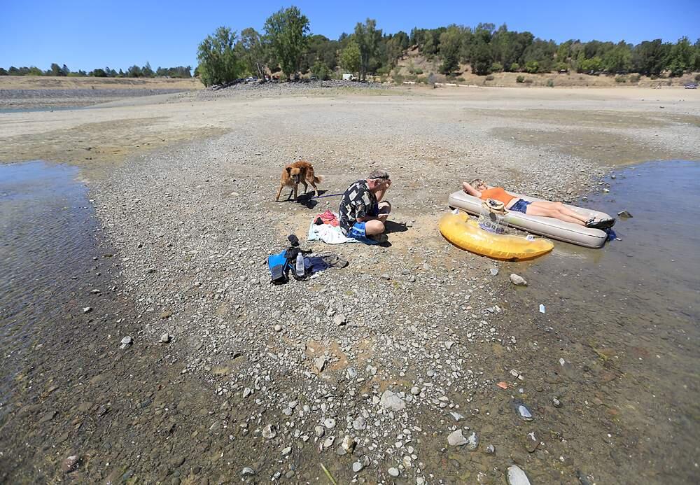 James Black of Grants Pass, Oregon, left and Rhonda Santos take in a day of swimming with their dog Echo on the dry lakebed of Lake Mendocino in Ukiah, Wednesday Aug. 14, 2013. (Kent Porter / Press Democrat) 2013