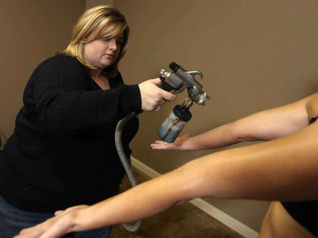 Kelly Richardson, owner of Sonoma Tanning in Santa Rosa, applies a spray tan on a client at her Larkfield facility, Jan. 20, 2010. (PD FILE PHOTO)