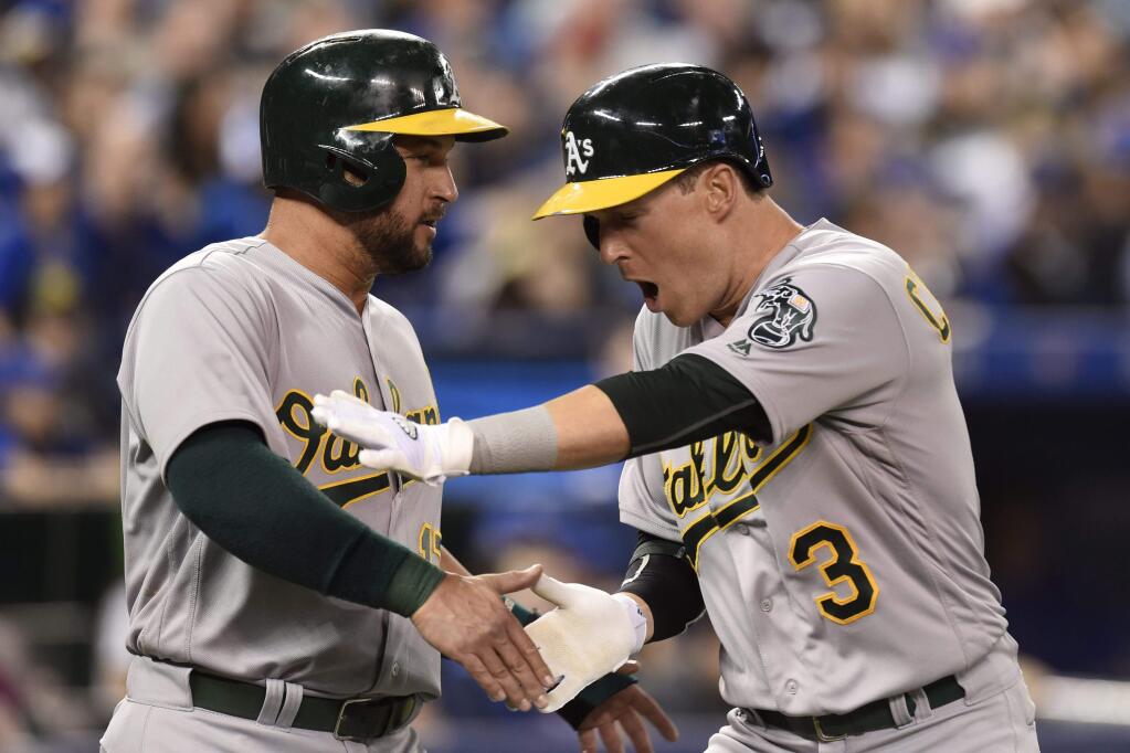 Oakland Athletics' Chris Coghlan (3) celebrates his three-run home run with teammate Yonder Alonso during the second inning against the Toronto Blue Jays on Friday, April 22, 2016, in Toronto. (Frank Gunn/The Canadian Press via AP)