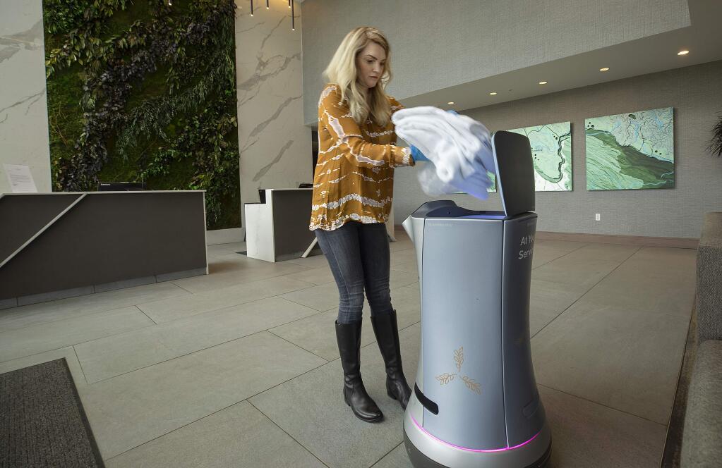 Brooke Ross, director of sales and marketing for Hotel Trio, loads towels and a bag of ice into Rose the Butler, a robot programmed to deliver items to guest rooms. The robot has helped with the social distancing at the Healdsburg hotel. (photo by John Burgess/The Press Democrat)