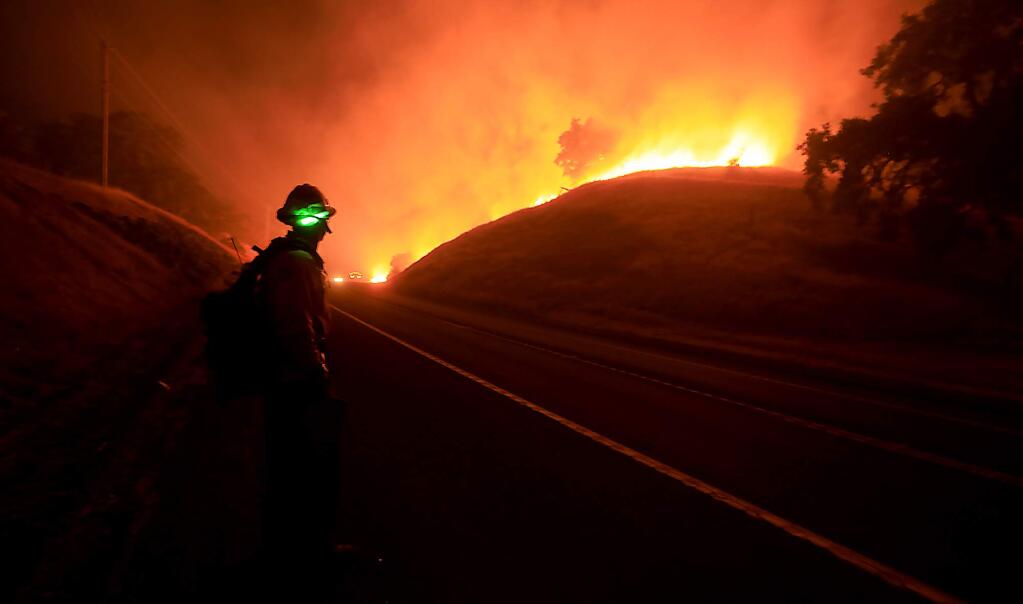 A firefighter from Santa Clara County monitors the Ranch fire as it slowly bumps Highway 20 near Bachelor Valley Road, Monday, July 30, 2018 in Upper Lake. (Kent Porter / The Press Democrat) 2018