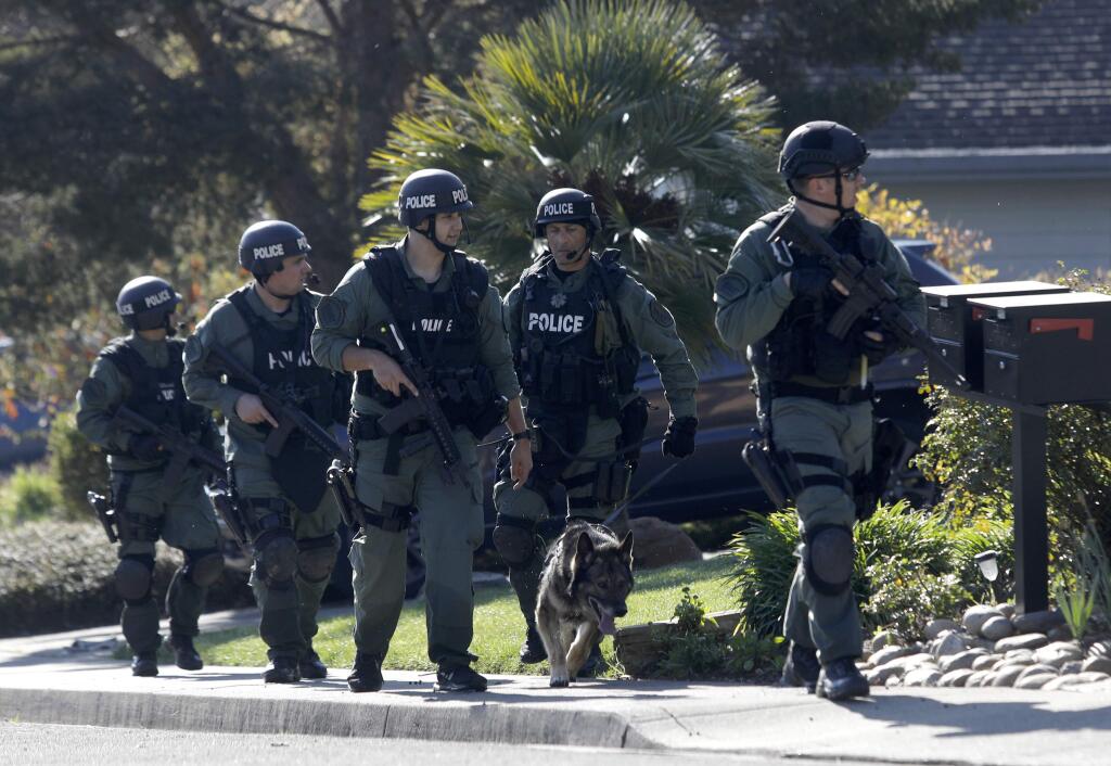 Members of the San Rafael-Novato SWAT team search a neighborhood in northern Novato for Petaluma home invasion suspects on March 12 . (BETH SCHLANKER / The Press Democrat)