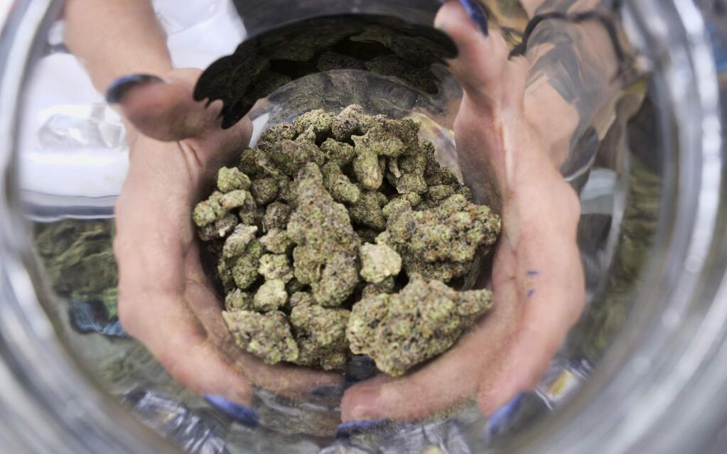 FILE - In this April 21, 2018, file photo a bud tender displays a jar of cannabis at the High Times 420 SoCal Cannabis Cup in San Bernardino, Calif. Businesses inside and outside the multibillion-dollar cannabis industry are using April 20, or “420,” to roll out marketing and social media messaging aimed at connecting with marijuana enthusiasts. (AP Photo/Richard Vogel, File)