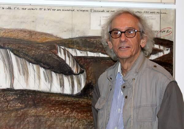 The artist Christo stands beside one of his 46 preparatory pencil, charcoal and pastel drawings for the Running Fence included in the Smithsonian exhibition 'Christo and Jeanne-Claude: Remembering the Running Fence.' Collage elements include technical data and a topographical map. This drawing is from 1976. (photo by Geneva Anderson)