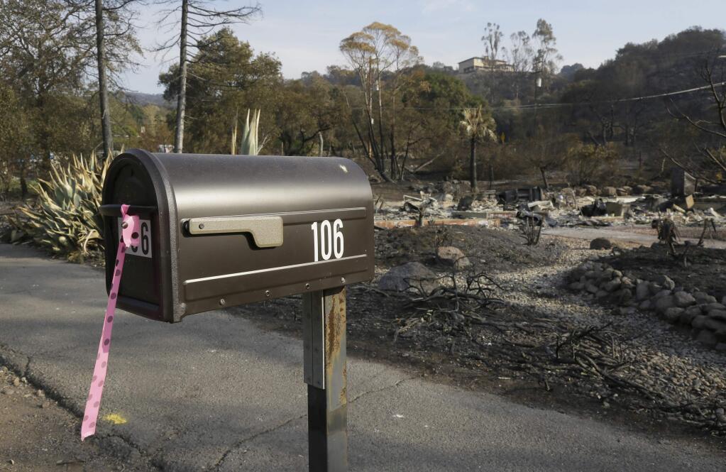 FILE - In this Oct. 16, 2017 file photo, a mailbox, one of few items left at the site of the destroyed home in Napa, Calif., where Sara and Charles Rippey died in a fast-moving wildfire, shows a pink and black polka dot ribbon that indicates a fire crew has visited the location. (AP Photo/Eric Risberg)