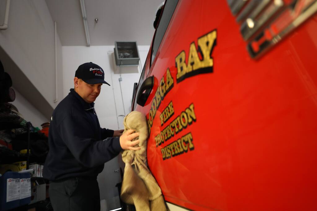 Probationary firefighter/paramedic David Tuttle wipes rainwater from a truck at the Bodega Bay Fire Protection District station in Bodega Bay on Wednesday, Dec. 11, 2019. (Beth Schlanker/The Press Democrat, 2019)