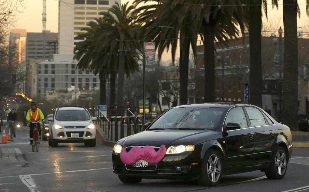 In this Jan. 17, 2013 file photo, a Lyft car drives crosses Market Street in San Francisco. In rulings filed Wednesday, March 11, 2015, two San Francisco federal judges said juries will have to decide whether former drivers for Uber and Lyft were independent contractors, or employees of the ride-hailing companies with all of the protections and benefits the state affords regular workers. The rulings have potentially expensive ramifications for Uber and Lyft. (AP Photo/Jeff Chiu, File)