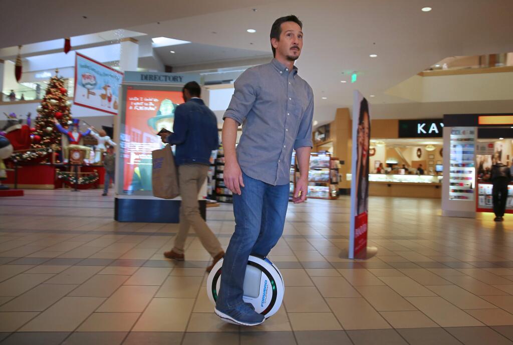Forward California founder Jake Bunch demonstrates the Ninebot One electric unicycle at his kiosk at the Santa Rosa Plaza, on Tuesday, December 15, 2015. Bunch expects to see more interest in his higher-end product, as problems mount for the 'hoverboard' devices.(Christopher Chung/ The Press Democrat)