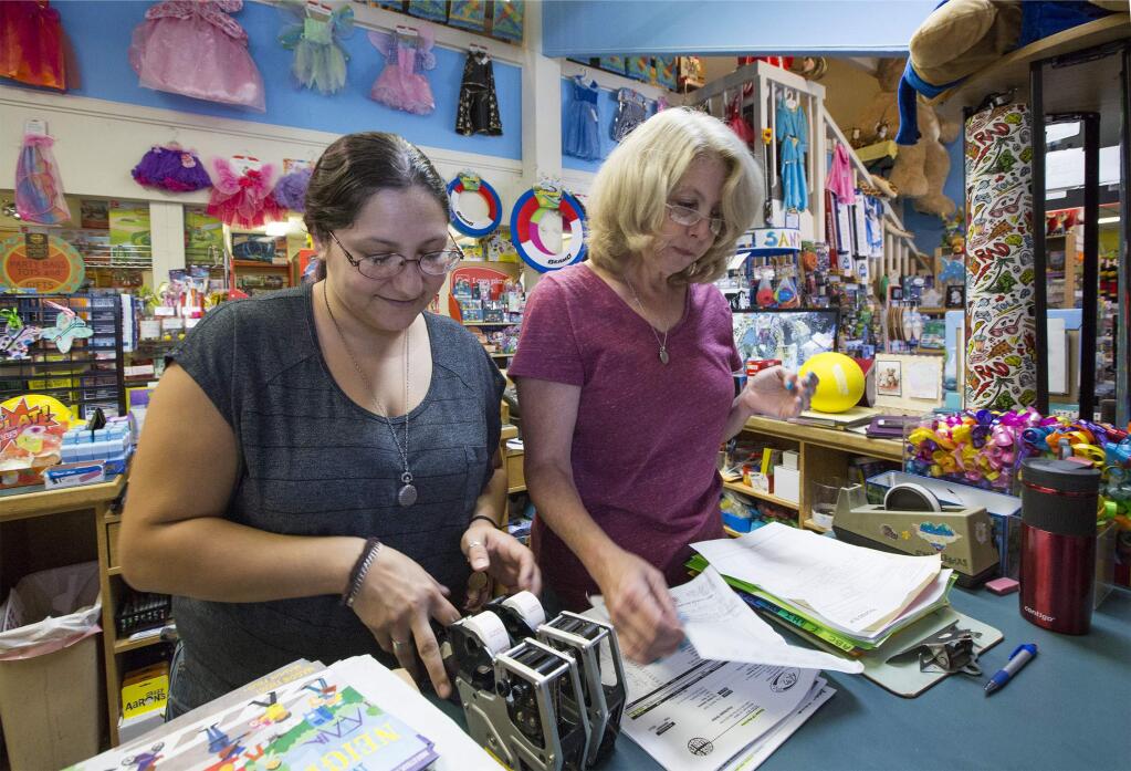 It's not always fun and games in a toy store. Assistant manager Jenna Haviland, left, helps store owner Michelle Boldt with the paperwork and the pricing.(Photo by Robbi Pengelly/Index-Tribune)
