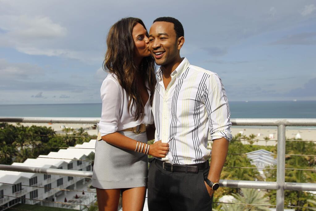 FILE - In this July 18, 2011 file photo, model Chrissy Teigen, left, and singer John Legend pose for photos after the Dineila Brazil swim suit show during the Mercedes-Benz Fashion Week in Miami Beach, Fla. Teigen and Legend announced on their Instagram accounts, Monday, Oct. 12, that they are expecting their first child. (AP Photo/J Pat Carter, File)