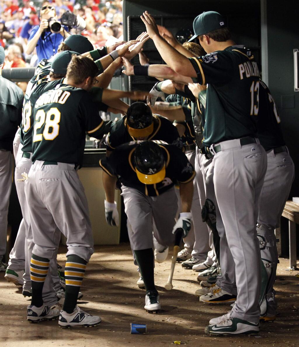 Oakland Athletics Billy Burns, front, and Marcus Semien celebrate with teammates after both scored on a hit by Josh Reddick against the Texas Rangers in the seventh inning of a baseball game Saturday, May 2, 2015, in Arlington, Texas. (AP Photo/Mike Stone)