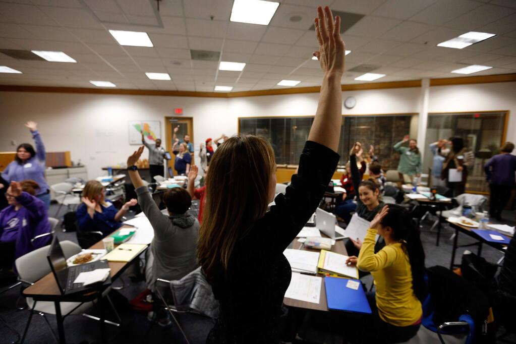 Class facilitator Sarah Lundy calls out, 'if you can hear my voice, raise your hand,' to refocus participants' attention up front during a small group exercise at the 'Teachers as Learners' class put on by the North Coast School of Education at the Sonoma County Office of Education in Santa Rosa, California on Tuesday, January 26, 2016. (Alvin Jornada / The Press Democrat)