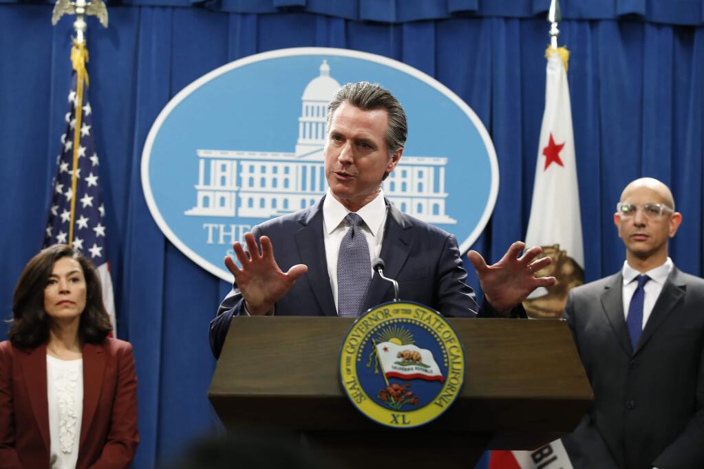 FILE - In this March 12, 2020 file photo, California Gov. Gavin Newsom speaks to reporters about the state's response to the coronavirus during a news conference in Sacramento, Calif. Newsom, a Democrat who leads the nation's most populous state, has won praise from both sides of the aisle for his approach to the coronavirus crisis though he's been less aggressive than some other governors and local leaders. Newsom is accompanied by California Department of Public Heath Director and State Health Officer Dr Sonia Angell, left, and California Health and Human Services Agency Director Dr. Mark Ghaly, right. (AP Photo/Rich Pedroncelli, File)