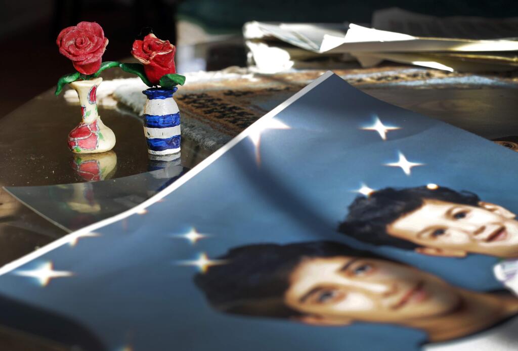 Prison artwork created by Adnan Syed sits near family photos in the home of his mother, Shamim Syed, Wednesday, Dec. 10, 2014, in Baltimore. Adnan Syed was convicted for the 1999 murder of his ex-girlfriend, and his case is being revived in a wildly popular podcast with millions of weekly listeners. A Maryland appeals court recently showed interest in the case and will hold a hearing in January weighing arguments that the man had ineffective counsel. (AP Photo/Patrick Semansky)