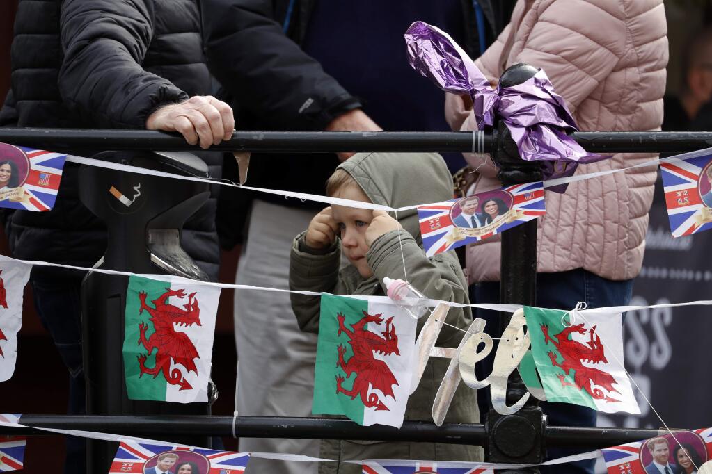 A young child adjusts his hood as people wait for the Royal Regiment of Scotland band, on the high street, in Windsor, south England, Tuesday, May 7, 2019, a day after Prince Harry announced that his wife Meghan, Duchess of Sussex, had given birth to a boy. The as-yet-unnamed baby arrived less than a year after Prince Harry wed Meghan Markle in a spectacular televised event on the grounds of Windsor Castle that was watched the world over. (AP Photo/Alastair Grant)
