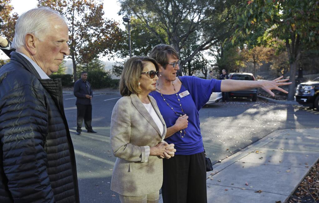 Naomi Fuchs, right, CEO of Santa Rosa Community Health, gestures beside Minority Leader Nancy Pelosi, D-Calif., and Rep. Mike Thompson, D-Calif., during a tour of the wildfire affected Vista campus on Saturday, Oct. 28, 2017, in Santa Rosa, Calif. (AP Photo/Ben Margot)