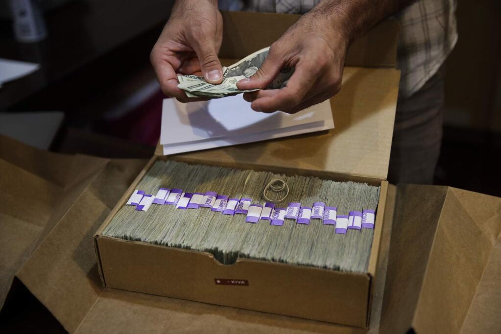FILE - In this June 27, 2017 file photo, the proprietor of a medical marijuana dispensary prepares his monthly tax payment, over $40,000 in cash, at his Los Angeles store. A proposal in Congress to ease the federal ban on marijuana could encourage more banks to do business with cannabis companies, but it appears to fall short of a cure-all for an industry that must operate mainly as a cash business in a credit card world. (AP Photo/Jae C. Hong, File)