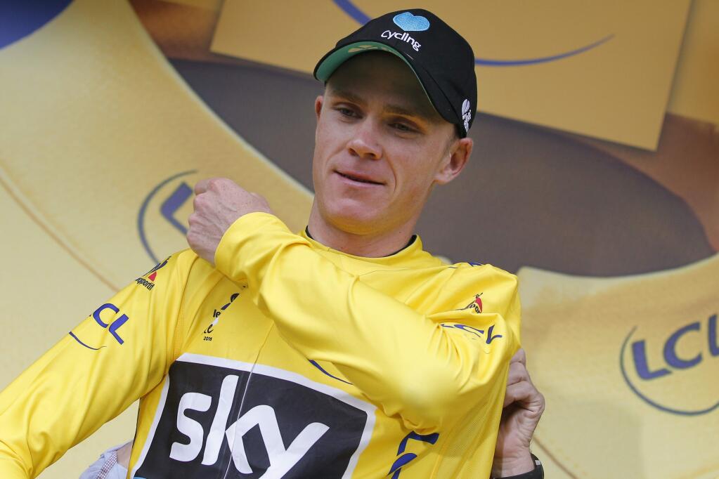 Britain's Chris Froome puts on the overall leader's yellow jersey on the podium after the nineteenth stage of the Tour de France cycling race over 146 kilometers (90.7 miles) with start in Albertville and finish in Saint-Gervais Mont Blanc, France, Friday, July 22, 2016. (AP Photo/Christophe Ena)