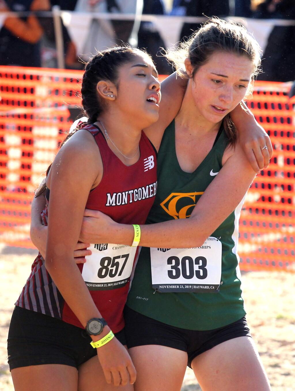 Mariah Briceno of Montgomery High, left, is hugged by Casa Grande's Emma Baswell after they finished the Division 3 girls race at the NCS cross country championships in Hayward on Saturday, Nov. 23, 2019. (Photo by Darryl Bush / For The Press Democrat)