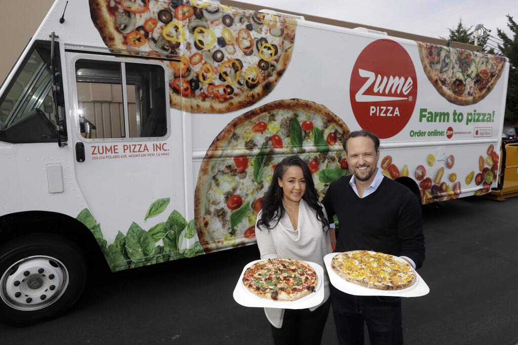 FILE - In this Aug. 29, 2016, file photo, CEO and co-founder Julia Collins, left, and co-founder Alex Garden pose for a photo in front of one of the company's delivery trucks at Zume Pizza in Mountain View, Calif. It has not been a good week for robots in the San Francisco Bay Area. A Silicon Valley company that used robots to make its pizzas closed this week and three coffee shops in downtown San Francisco that used robots as baristas also shuttered. Zume Pizza said it is cutting 172 jobs in Mountain View, and eliminating another 80 jobs at its facility in San Francisco. Zume Chief Executive Alex Garden made the announcement about Zume in an email to company employees on Wednesday, Jan. 8, 2020, the Mercury News reported. (AP Photo/Marcio Jose Sanchez, File)