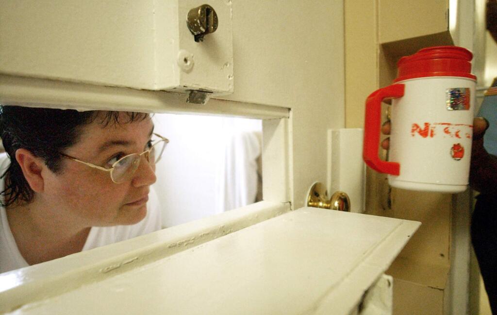 FILE -In this Tuesday, July 6, 2004, file photo, Kelly Gissendaner, the only woman on Georgia's death row, peers through the slot in her cell door as a guard brings her a cup of ice at Metro State Prison in Atlanta. Gissendaner was scheduled to be executed Monday, March 2, 2015, but citing concerns about the drug to be used in a lethal injection, corrections officials in Georgia postponed Gissendaner's execution for the second time in a week. (AP Photo/Atlanta Journal-Constitution, Bita Honarvar, File)
