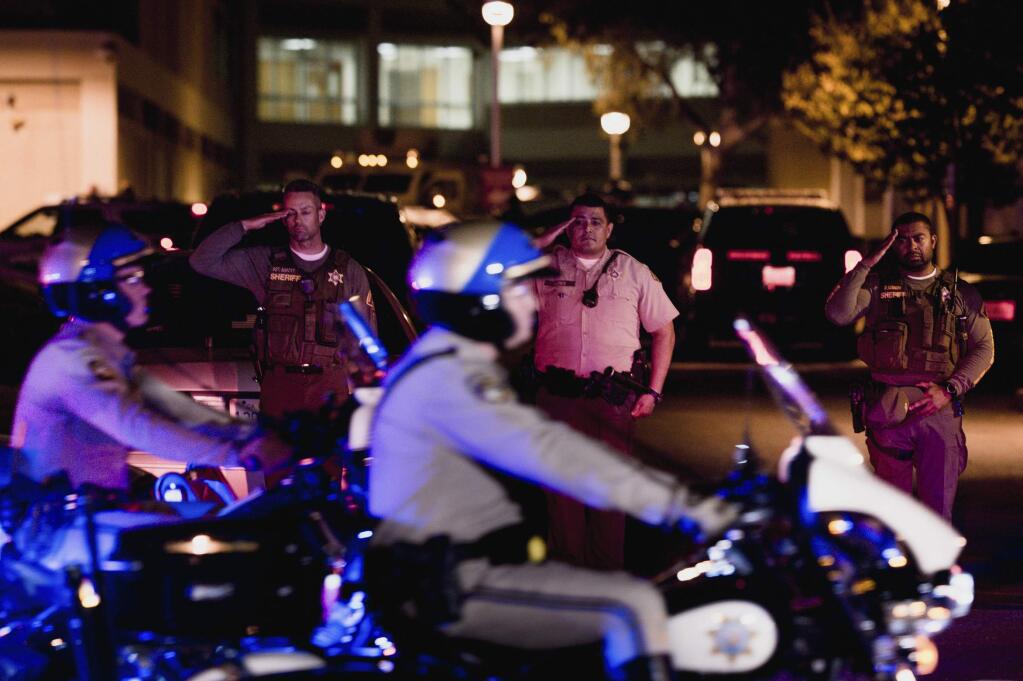 Sheriff deputies salute as California Highway Patrol motorcycle officers lead the procession for a fallen California Highway Patrol officer at Riverside University Health System Medical Center in Moreno Valley, Calif., on Monday, Aug 12, 2019. Moye was killed during a shootout following a traffic stop in Riverside. (Watchara Phomicinda/The Orange County Register via AP)