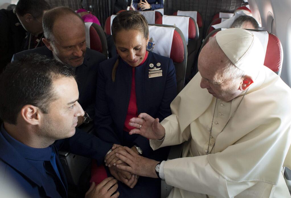 Pope Francis marries flight attendants Carlos Ciuffardi, left, and Paola Podest, center, during a flight from Santiago, Chile, to Iquique, Chile, Thursday, Jan. 18, 2018. Pope Francis celebrated the first-ever airborne papal wedding, marrying these two flight attendants from Chile's flagship airline during the flight. The couple had been married civilly in 2010, however, they said they couldn't follow-up with a church ceremony because of the 2010 earthquake that hit Chile. (L'Osservatore Romano Vatican Media/Pool Photo via AP)