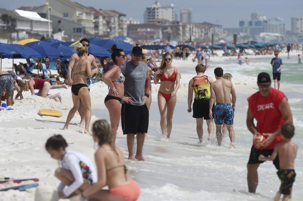 Beachgoers enjoy a sunny day in Destin, Fla., Wednesday, March 18, 2020. There's a new type of social policing out there that's developed almost as quickly as the viral disease that spurred its arrival. It's called 'quarantine shaming,' calling out those who are leaving the house for daily activities or who aren't abiding by social distancing rules. And it's part of a new reality for Americans who must navigate a world of rapidly evolving social norms in the age of COVID-19. (Devon Ravine/Northwest Florida Daily News via AP, File)