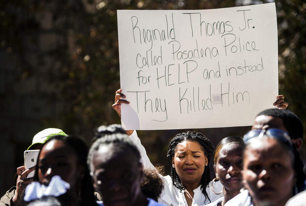 A supporter for Reginald Thomas holds a sign protesting the Pasadena Police as the family of Reginald Thomas share witness accounts of the death of Thomas during a press conference in front of the Pasadena Police Department in Pasadena, Calif., Monday, Oct. 3, 2016. On Friday, Reginald Thomas died after being shot with a Taser by police in Pasadena. He was armed with a knife and his wife described him as mentally ill. (Watchara Phomicinda/The Pasadena Star-News/SCNG via AP)
