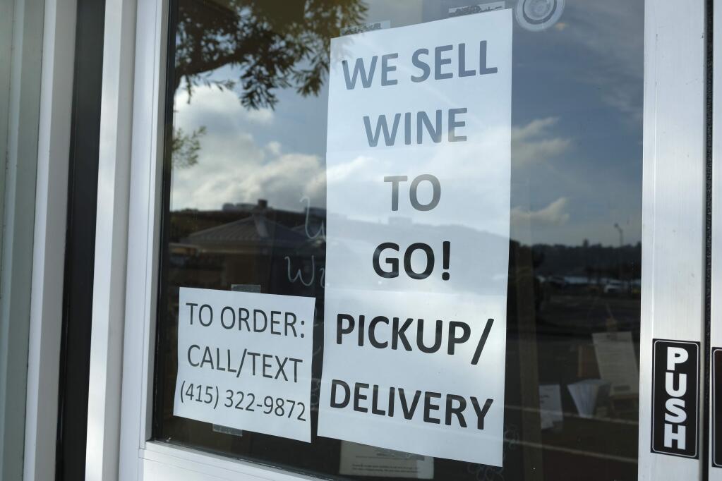 A sign in the window of The Bacchus & Venus advertises they are selling wine to go Tuesday, March 17, 2020, in Sausalito, Calif. About 7 million people in the San Francisco Bay Area woke up Tuesday to nearly empty highways, shuttered stores and vacant streets after officials issued an order for residents to shelter at their homes and only leave for 'essential' reasons in a desperate attempt to slow the spread of the coronavirus. (AP Photo/Eric Risberg)