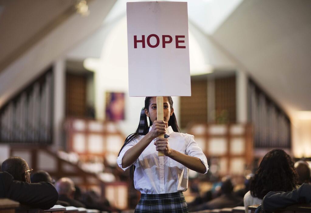 Jaiya Smith carries a sign down the aisle during a service honoring Rev. Martin Luther King Jr. at Ebenezer Baptist Church, where King preached, Monday, Jan. 19, 2015, in Atlanta. (AP Photo/David Goldman)