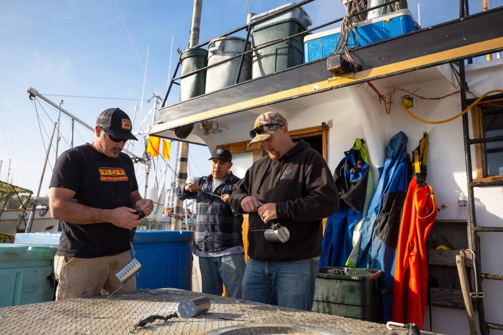Deckhands Chris Ponts, left, Wilton Cruz, and Eric McGuire prepare bait canisters aboard the fishing vessel Blackhawk while the boat is docked at Spud Point Marina in Bodega Bay, California, on Thursday, January 30, 2020. (Alvin Jornada / The Press Democrat)
