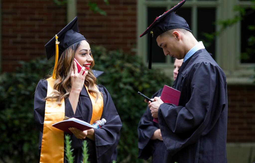 Graduates, Jessica Avila of Santa Rosa, and Cristian Gutierrez of Rohnert Park, use their phones in line before the 2017 Commencement at Santa Rosa Junior College, in Santa Rosa, Calif., on Saturday, May 27, 2017. (Photo by Darryl Bush / For The Press Democrat)