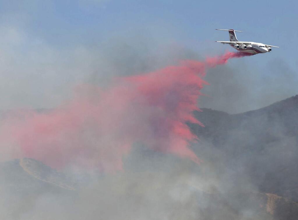 A plane drops fire retardant on the Sand Fire as it burns in the hills east of Sand Canyon Road and Soledad Canyon Road in Canyon Country on Friday, July 22, 2016. A wildfire north of Los Angeles has now burned about 2.3 square miles of bone-dry hillside. The fire erupted shortly after 2 p.m. Friday next to State Route 14 in Santa Clarita. The freeway is partially closed along with a section of Metrolink train track. About 200 firefighters and a half-dozen aircraft are battling the flames in 106-degree heat. (Katharine Lotze/The Santa Clarita Valley Signal via AP)EDIT