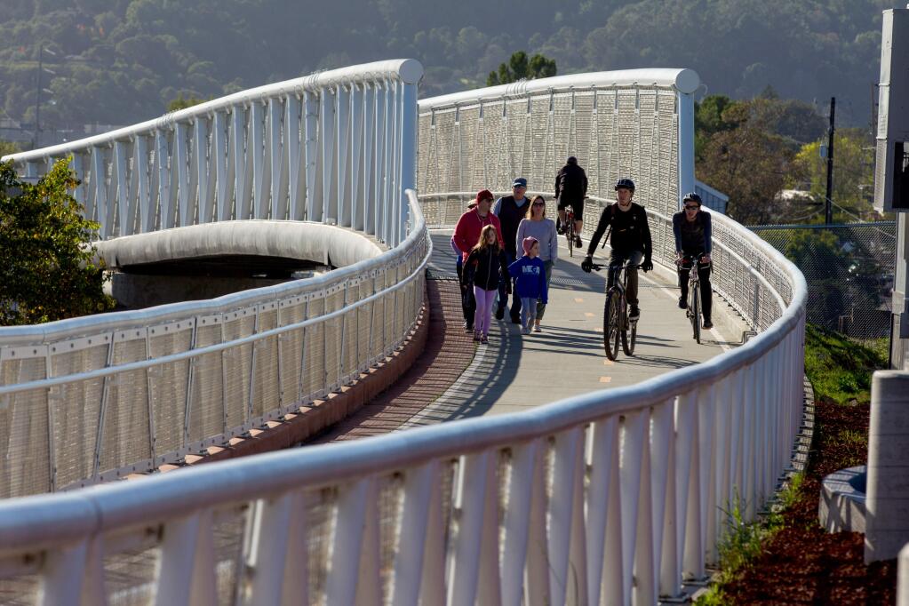 People bike and walk over a bridge as they go to the newly opened Larkspur SMART Train Station that crosses over Sir Francis Drake Blvd. from the area of Larkspur Ferry Terminal, in Larkspur, Calif., on Saturday, December 14, 2019. (Photo by Darryl Bush / For The Press Democrat)