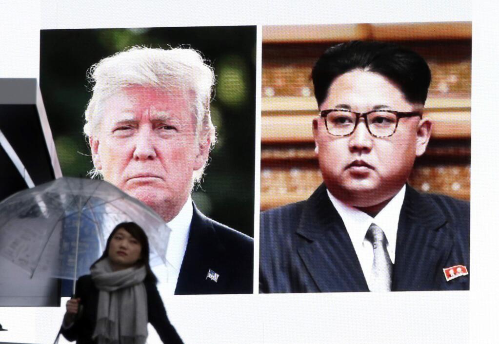 A woman walks by a huge screen showing U.S. President Donald Trump, left, and North Korea's leader Kim Jong Un, in Tokyo, Friday, March 9, 2018. After a year of threats and diatribes, U.S. President Donald Trump and third-generation North Korean dictator Kim Jong Un have agreed to meet face-to-face for talks about the North's nuclear program.(AP Photo/Koji Sasahara)