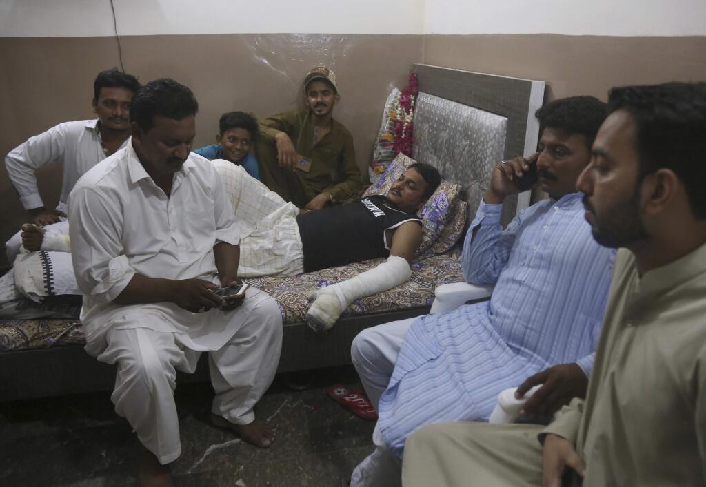 Relatives visit with Mohammad Zubair, a passenger who survived a plane crash, at his home in Karachi, Pakistan, Saturday, May 23, 2020. When the plane jolted violently, Zubair thought it was turbulence. Then the pilot came on the intercom to warn that the landing could be 'troublesome.' Moments later, the Pakistan International Airlines flight crashed into a crowded neighborhood near Karachi's international airport. (AP Photo/Fareed Khan)