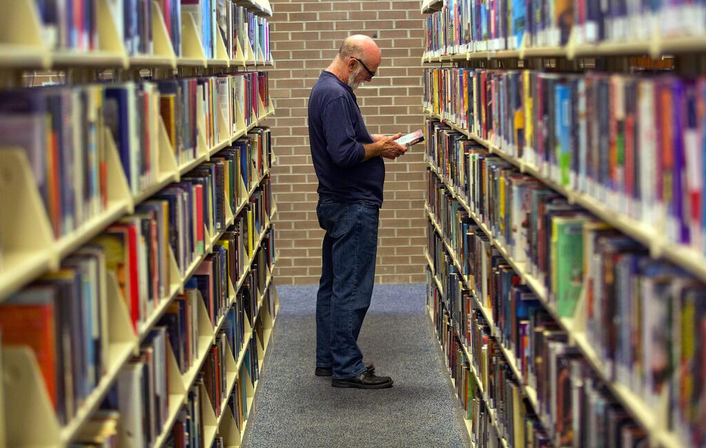 Jim Tulip peruses the mystery aisle at the main branch of the Sonoma County Library in Santa Rosa on Tuesday. (John Burgess/The Press Democrat)