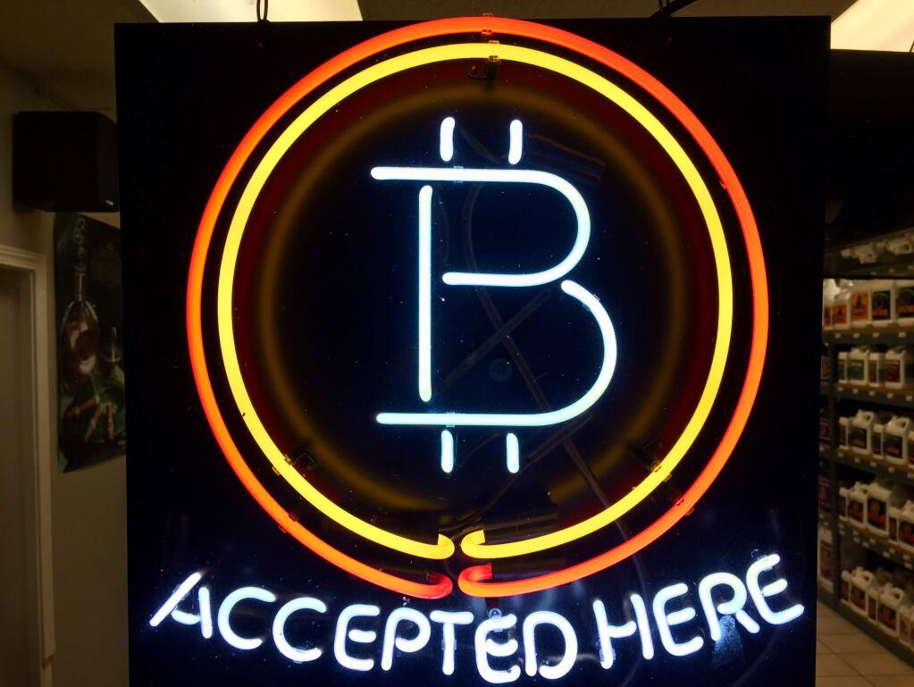 A neon sign hanging in the window of Healthy Harvest Indoor Gardening in Hillsboro, Oregon, shows that the business accepts bitcoin as payment. (AP Photo/Gillian Flaccus) Feb. 7, 2018
