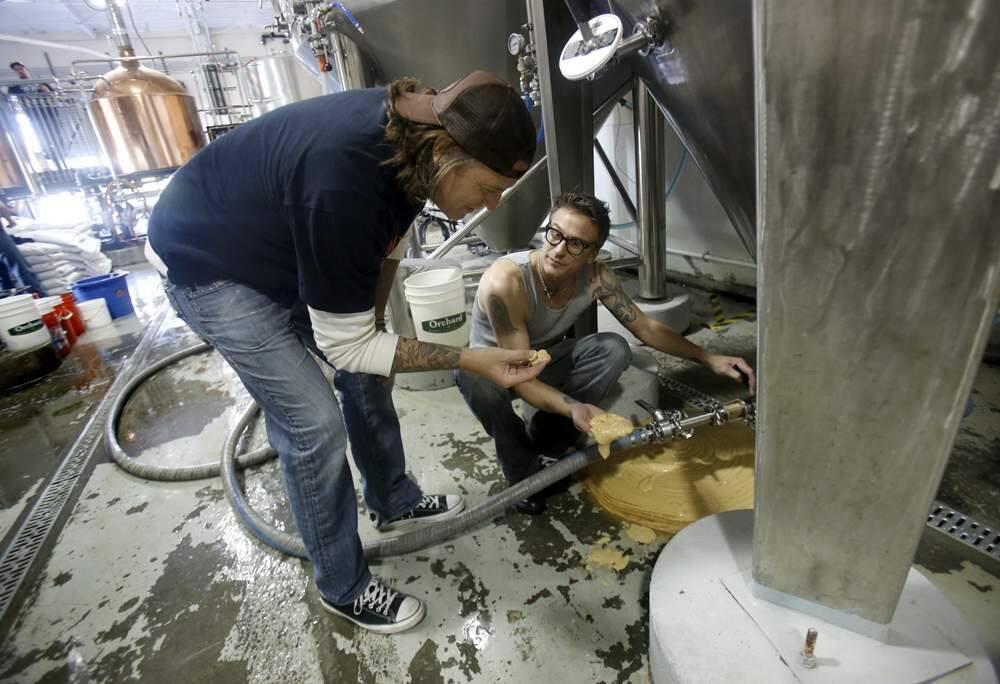 Brothers and co-owners Jake, left, and Joel Johnson look at the yeast of a red rye beer as it drains from a fermenter at the newly opened 101 North Brewing Company on Thursday, April 25, 2013 in Petaluma, California. (BETH SCHLANKER/ The Press Democrat)