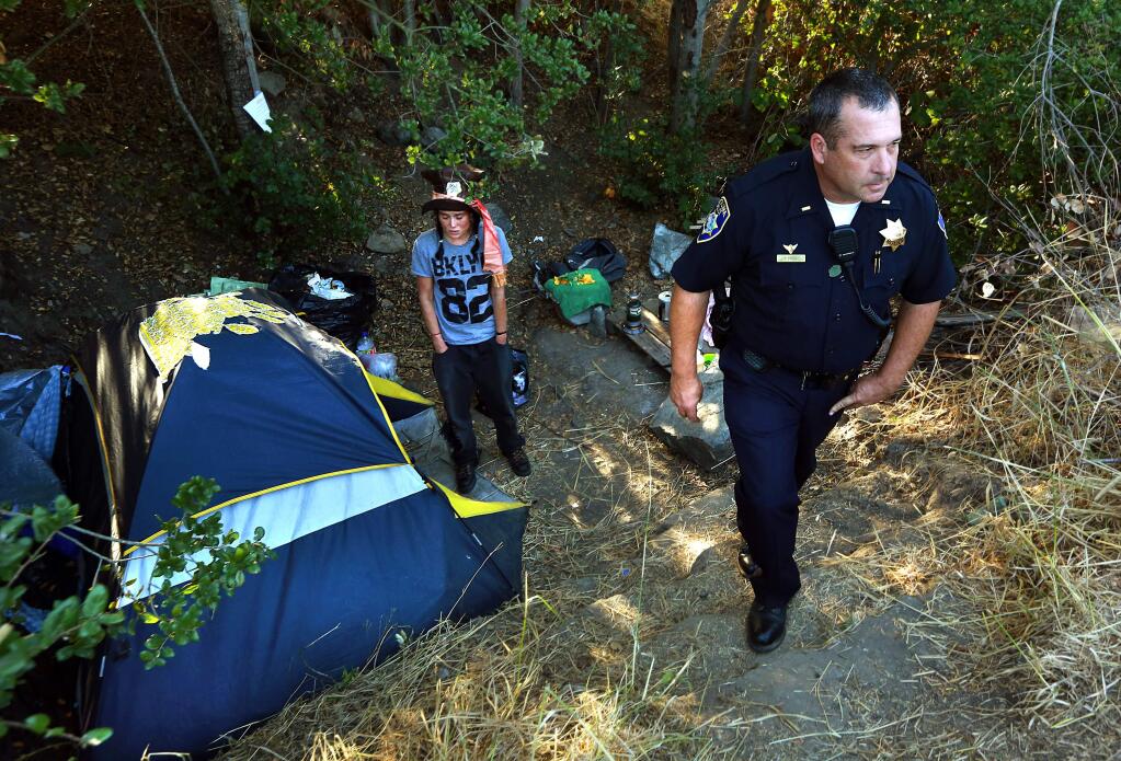Petaluma Police Lt. Tim Lyons gives notice to a homeless woman she will have to move on from her encampment behind the Clover garage near the Petaluma River and the railroad tracks. (JOHN BURGESS/ PD)