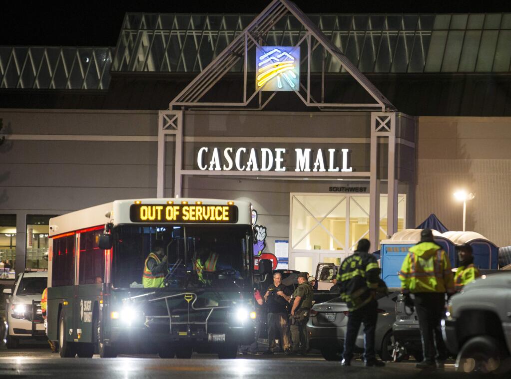 Emergency personnel stand in front of an entrance to the Cascade Mall at the scene of a shooting where several people were killed Friday, Sept. 23, 2016, in Burlington, Wash. Police searched Saturday for a gunman who opened fire in the makeup department of a Macy's store at the mall north of Seattle, killing several females, before fleeing toward an interstate on foot, authorities said. (AP Photo/Stephen Brashear)