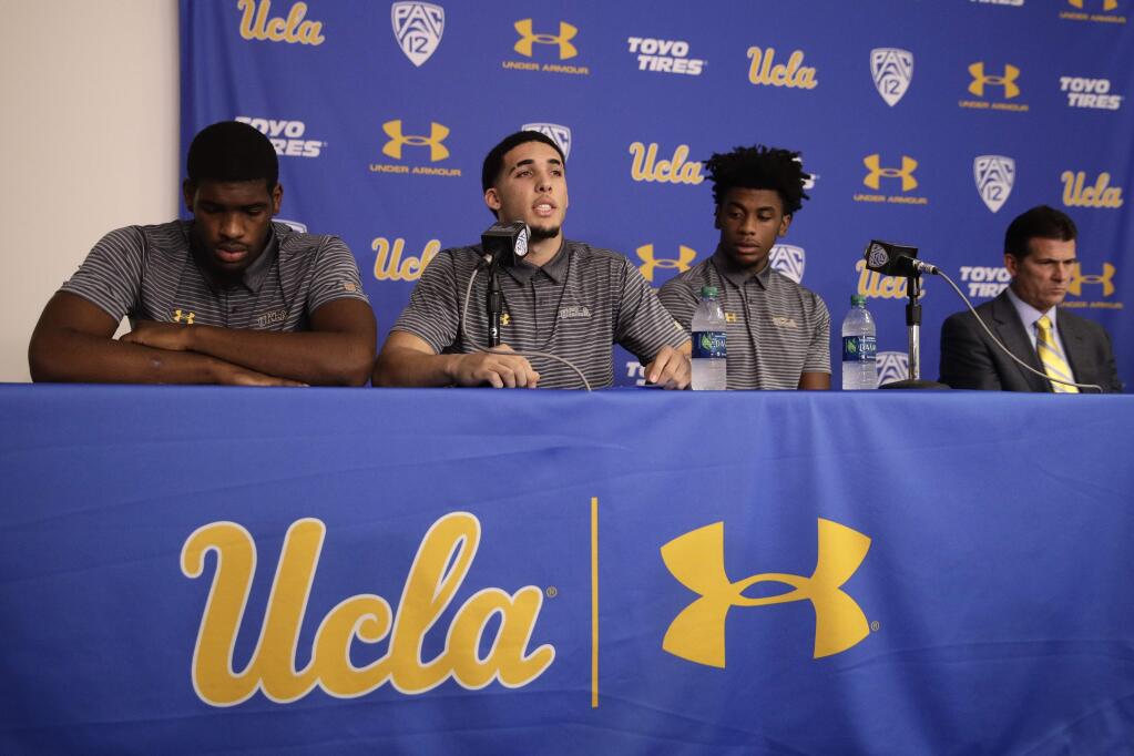 Flanked by Cody Riley, left, and Jalen Hill, third from left, UCLA basketball player LiAngelo Ball reads his statement as head coach Steve Alford listens during a news conference at UCLA Wednesday, Nov. 15, 2017, in Los Angeles. The three players were detained in Hangzhou following allegations of shoplifting last week before an NCAA college basketball game against Georgia Tech in Shanghai. (AP Photo/Jae C. Hong)