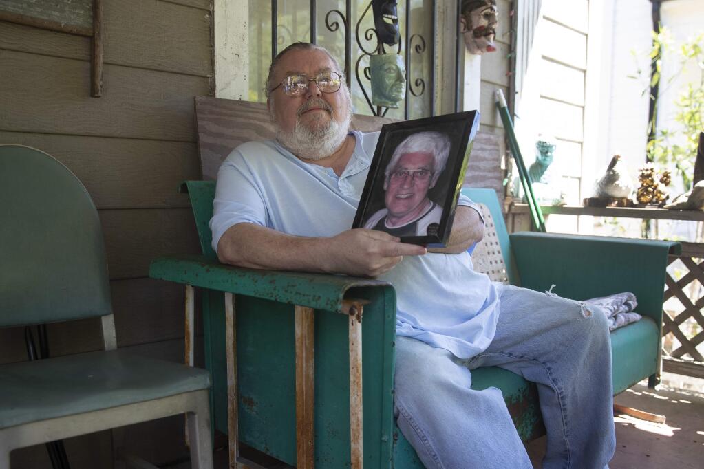 James Kelly poses with a photo of his late father also named James Kelly at his home Friday, May 1, 2020. Kelly had to delay his plans to travel Scotland, where he planned to scatter his father's ashes, because of the coronavirus outbreak (AP Photo/John Bazemore)
