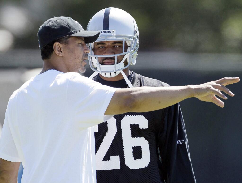 FILE - In this July 29, 2011, file photo, Oakland Raiders cornerback Stanford Routt, right, listens to assistant defensive backs coach Rod Woodson, left, during their NFL football training camp in Napa, Calif. The Oakland Raiders brought in 10 men with 102 years of playing experience, 15 Pro Bowl appearances, five All-Pro selections and one Hall of Famer this offseason. That's just on the coaching staff. (AP Photo/Eric Risberg, File)