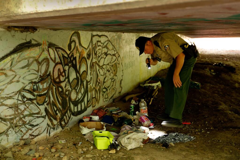 Sonoma County sheriff's deputy Dan Mori looks over a vacant homeless encampment beneath the Fife Creek bridge in Guerneville, California, on Tuesday, May 16, 2017. (Alvin Jornada / The Press Democrat)