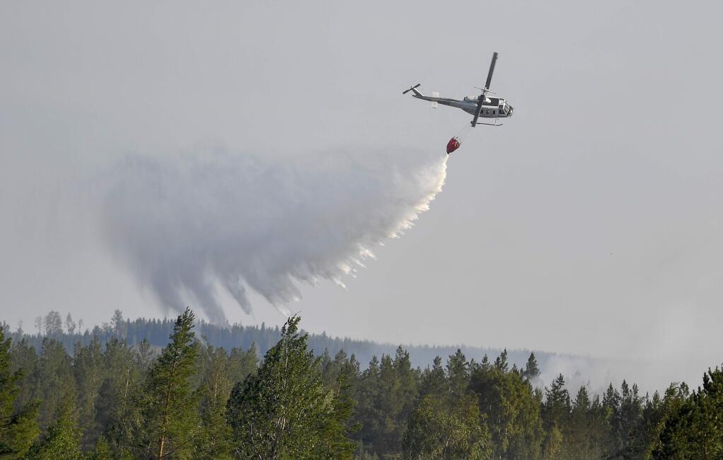 An aircraft helps to stop the advancing wildfire near to homes, outside Ljusdal, Sweden, Tuesday July 17, 2018. This is one of about 80 wildfires reported in Sweden, due to the dry weather. (Maja Suslin / TT via AP)