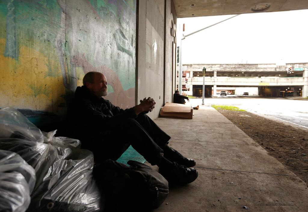 Doug Thompson, 60, sits beneath the Highway 101 overpass at Fifth Street with his belongings. Thompson, who has lived in the Santa Rosa area for 50 years, became homeless two years ago after his mother died. (ALVIN JORNADA / The Press Democrat)
